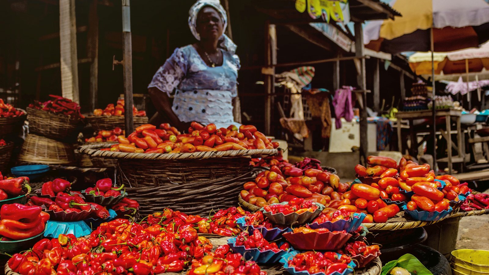 Marktkoopvrouw verkoopt pepers in Nigeria